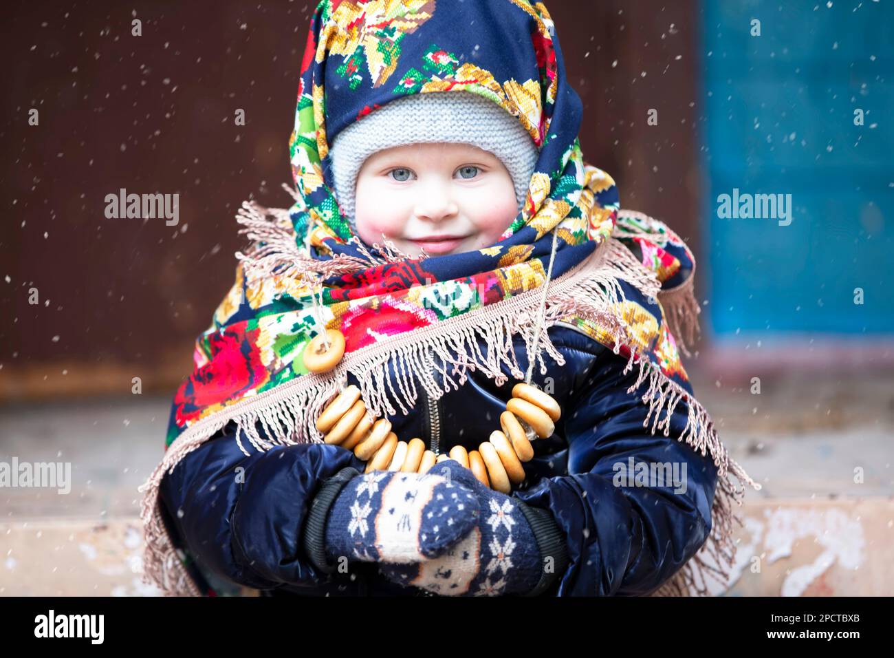 Una bambina in un velo russo con bagel durante la vacanza Maslenitsa. Foto Stock