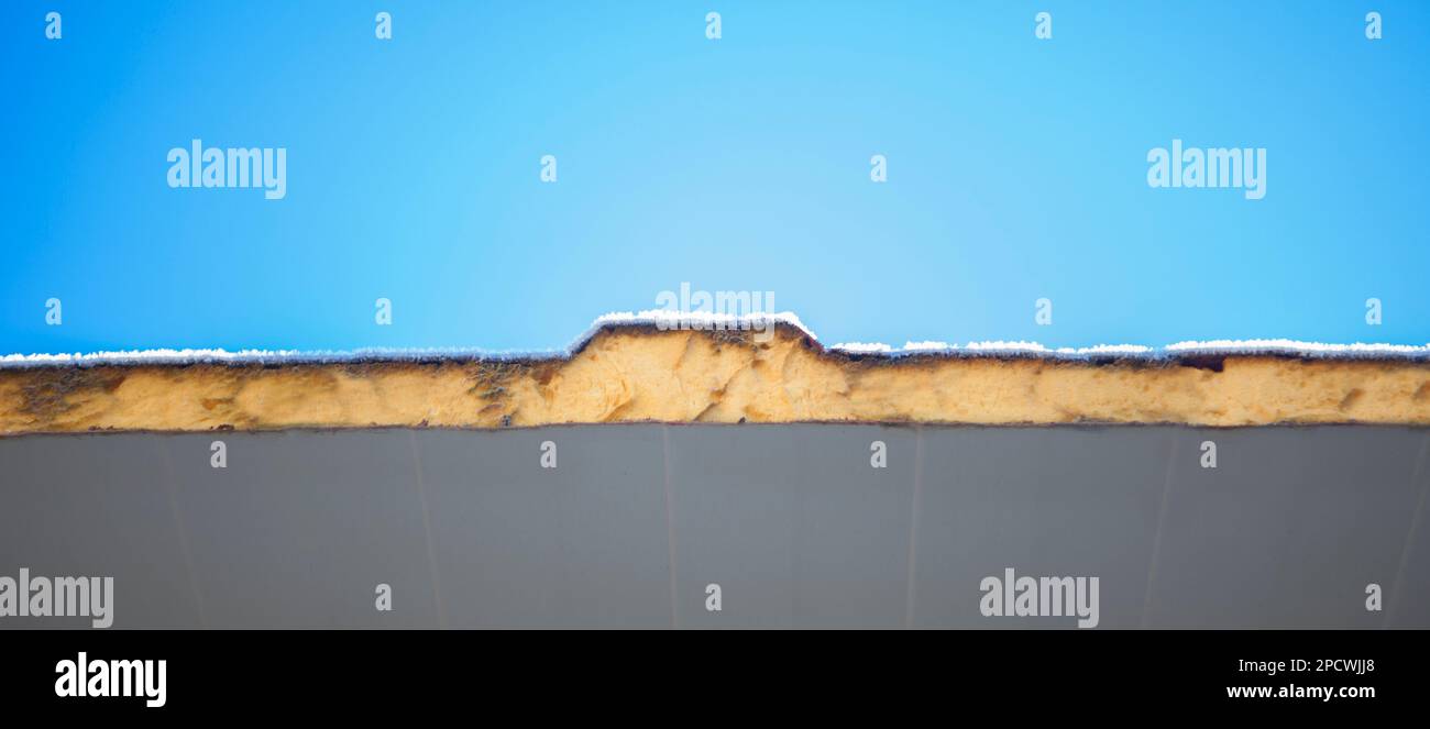 Tetto isolato con pannelli sandwich e coperto con gelo invernale. Sfondo cielo blu Foto Stock