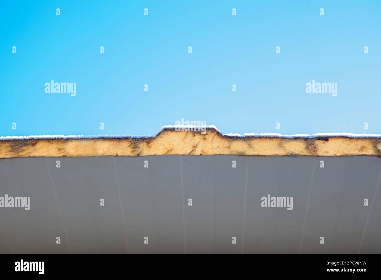 Tetto isolato con pannelli sandwich e coperto con gelo invernale. Sfondo cielo blu Foto Stock