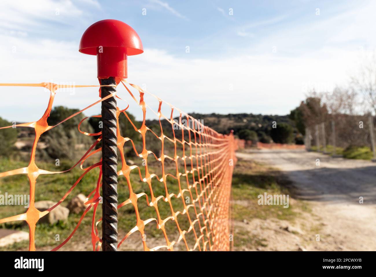 primo piano di una recinzione arancione con un palo che sporge da essa. Barriera o rete di protezione per cantiere. Messa a fuoco selettiva Foto Stock