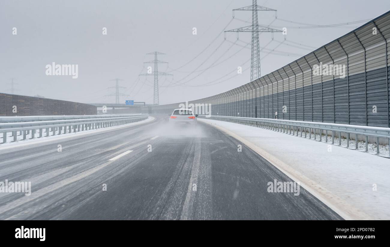 Auto sorpasso un'altra macchina su una strada ghiacciata (Autobahn tedesco). Simbolo di guida pericolosa su una strada sdrucciolevole. Foto Stock
