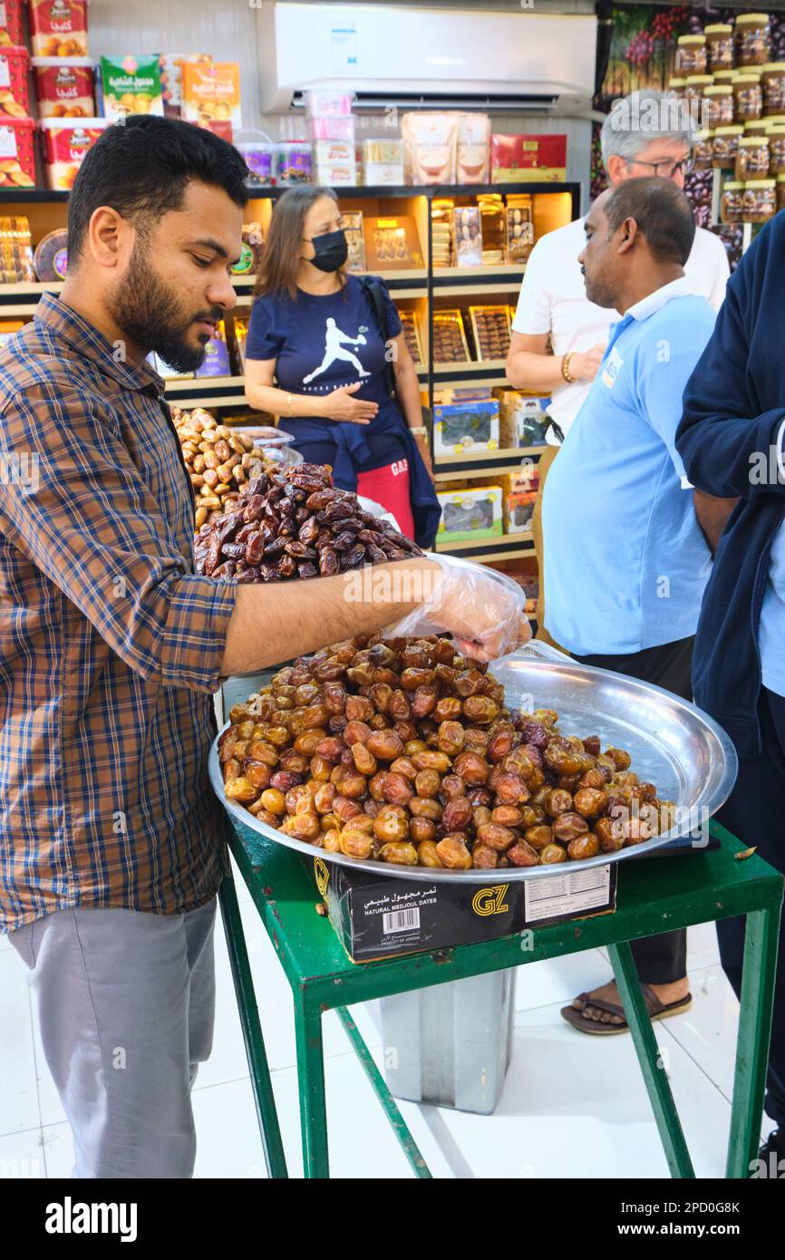 Un fornitore del negozio che offre campioni gratuiti per la degustazione di date. Alla data, il mercato della frutta secca ad Abu Dhabi, Emirati Arabi Uniti. Foto Stock