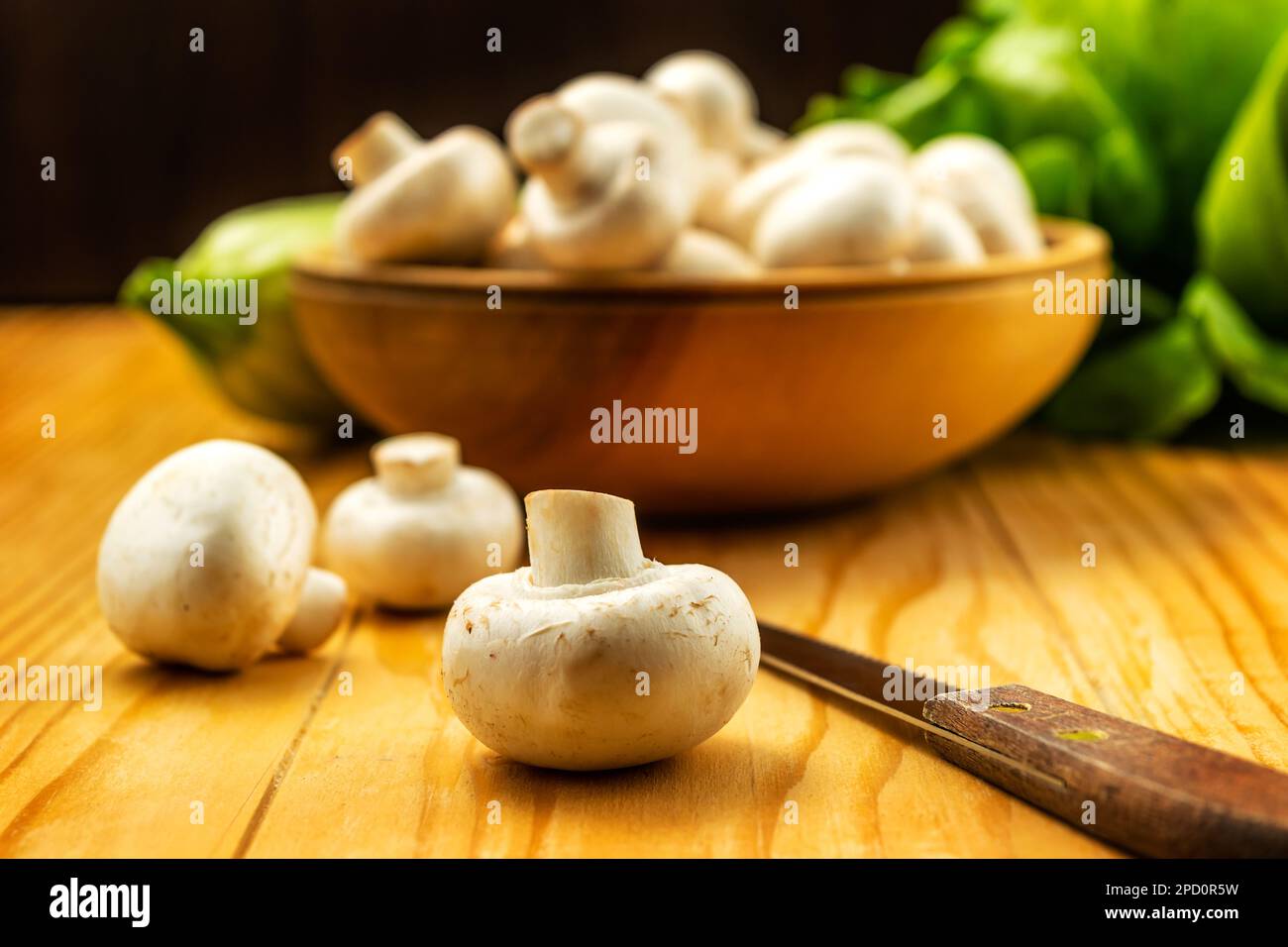 Funghi bianchi freschi champignon in ciotola di legno marrone su sfondo tavolo di legno Foto Stock
