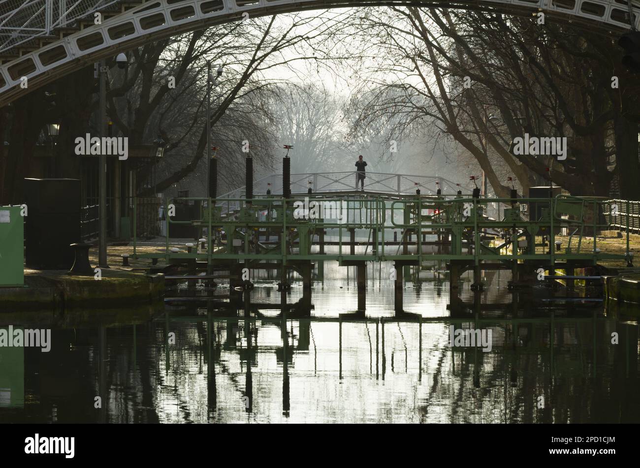 Uomo, persona che scatta una fotografia di una serratura da Un ponte pedonale al mattino presto, Canal Saint Martin, Parigi Foto Stock