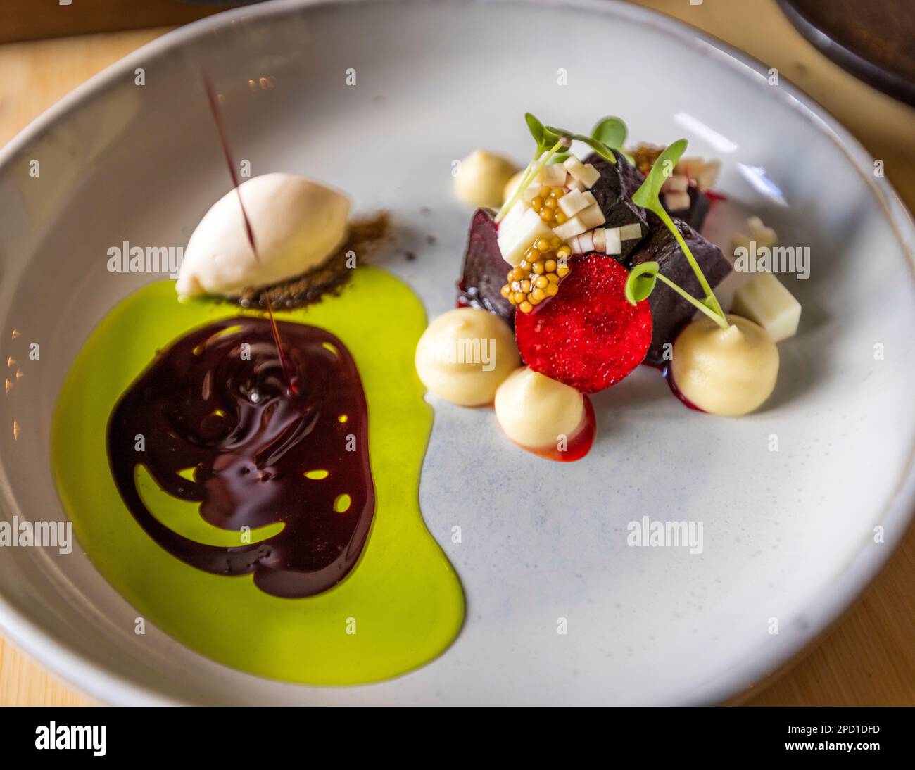 Antipasto al ristorante WKK, Wilde Kloster Küche, dello chef Manuel Burke, Neuzelle, Germania. Riduzione dell'olio di barbabietola e aneto versato su gelato al sedano, gelato al formaggio di capra e barbabietola rossa. Foto Stock