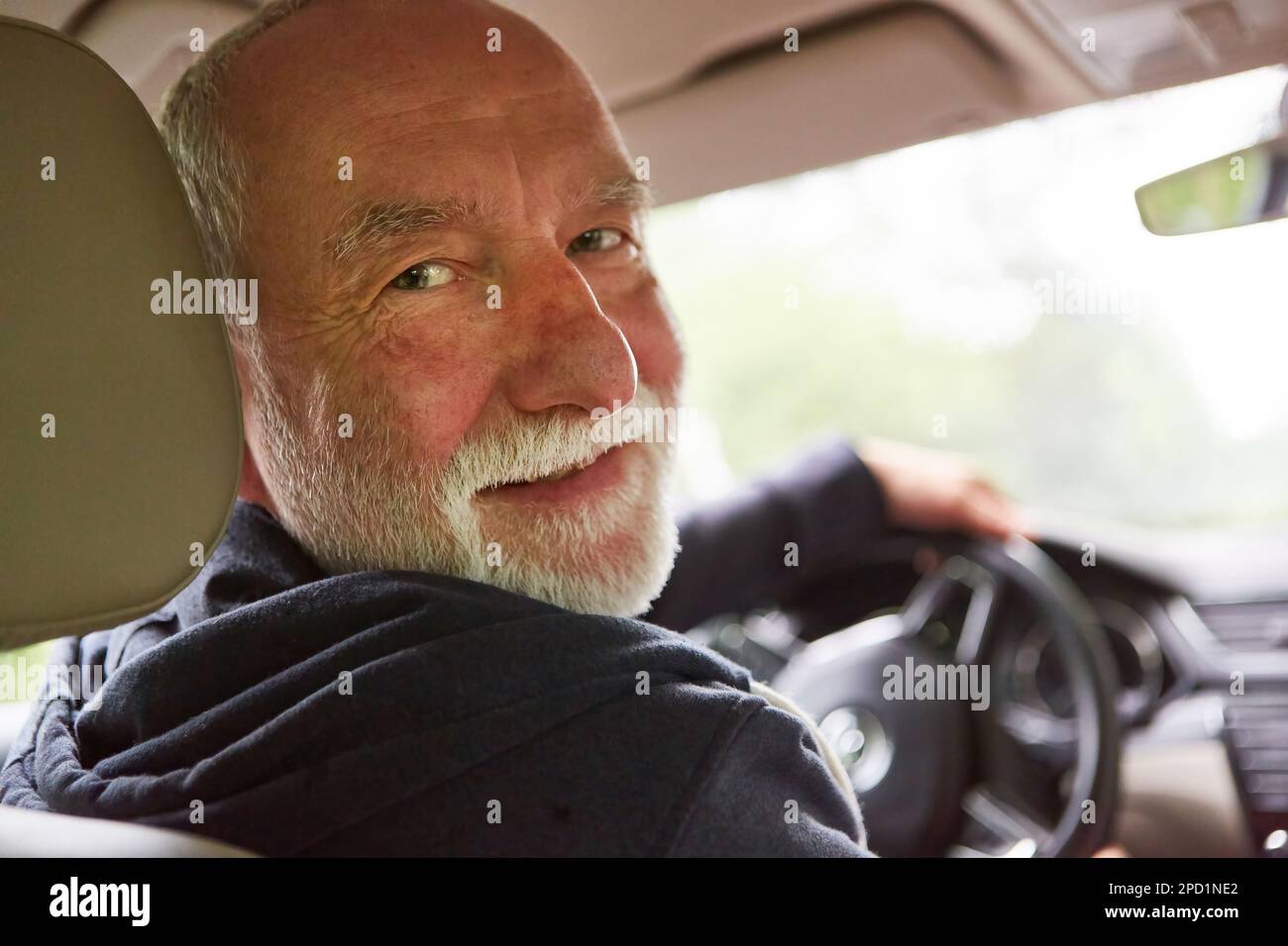 Ritratto di un uomo anziano sorridente seduto in auto durante un viaggio in vacanza Foto Stock