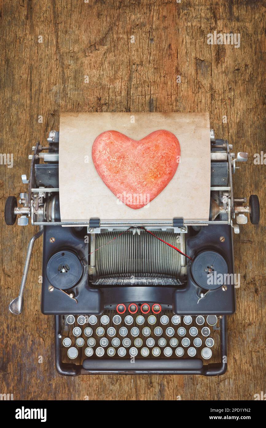 Vista dall'alto di una macchina da scrivere vintage con cuore rosso su un foglio di carta Foto Stock