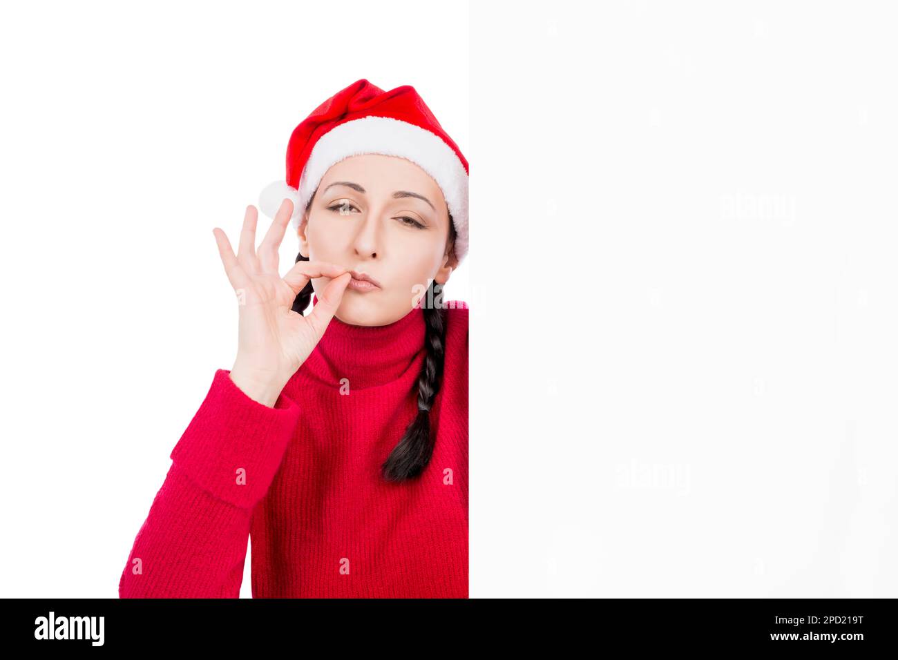 Ragazza a Santa Hat fare ok gesto positivo da dietro bianco pubblicità cartello pannello isolato su uno sfondo bianco. Concetto di vendita. Foto Stock