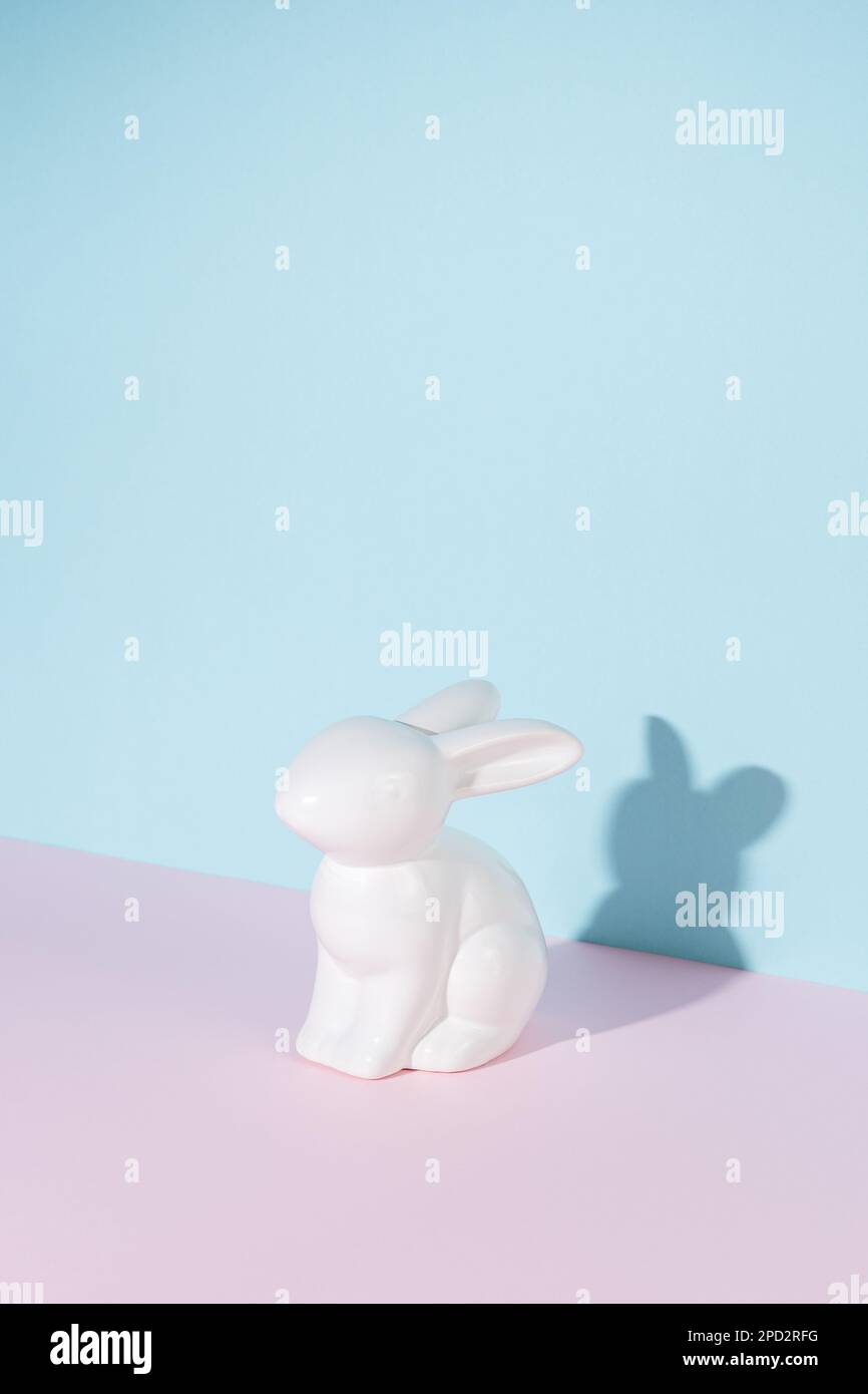 Coniglietto pasquale in porcellana o coniglio con ombre nitide su sfondo luminoso. Concetto creativo di Pasqua minima. Foto Stock
