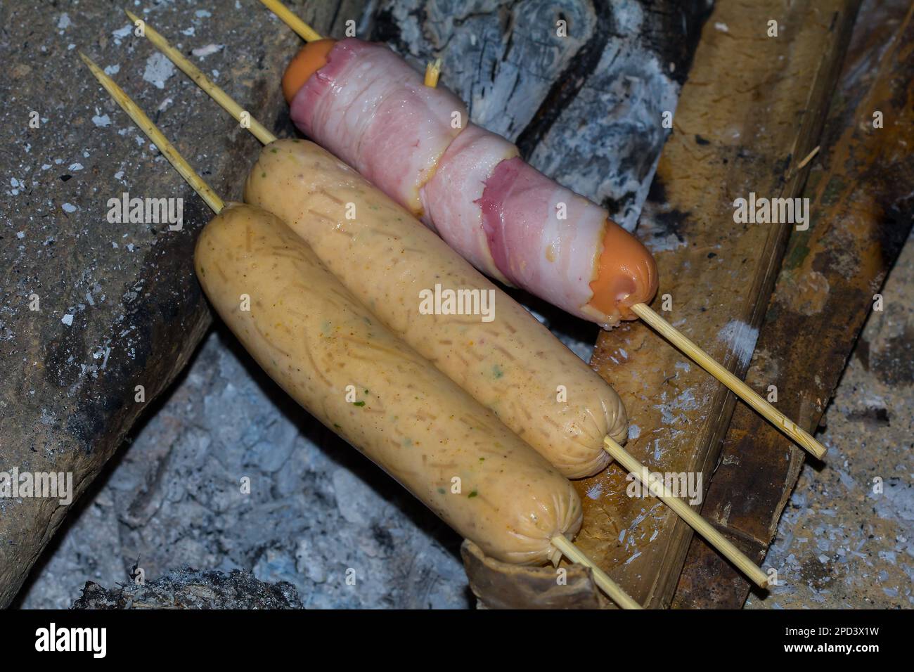 Le salsicce vengono grigliate su un mucchio di carbone caldo. Foto Stock