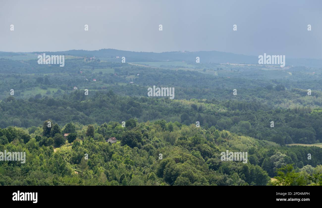 Paesaggio rurale in estate con condizioni meteorologiche multiple, luogo di sole sulla casa rurale circondata da una foresta lussureggiante e villaggio sparso con cupo Foto Stock