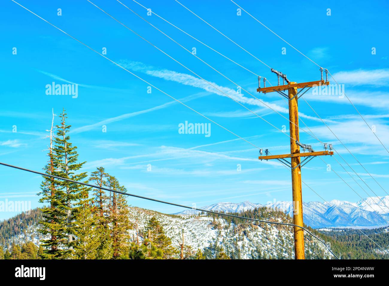 Palo di potenza in legno con fili sullo sfondo di montagne e un cielo blu chiaro. Fornitura di energia elettrica affidabile in aree remote. Foto Stock