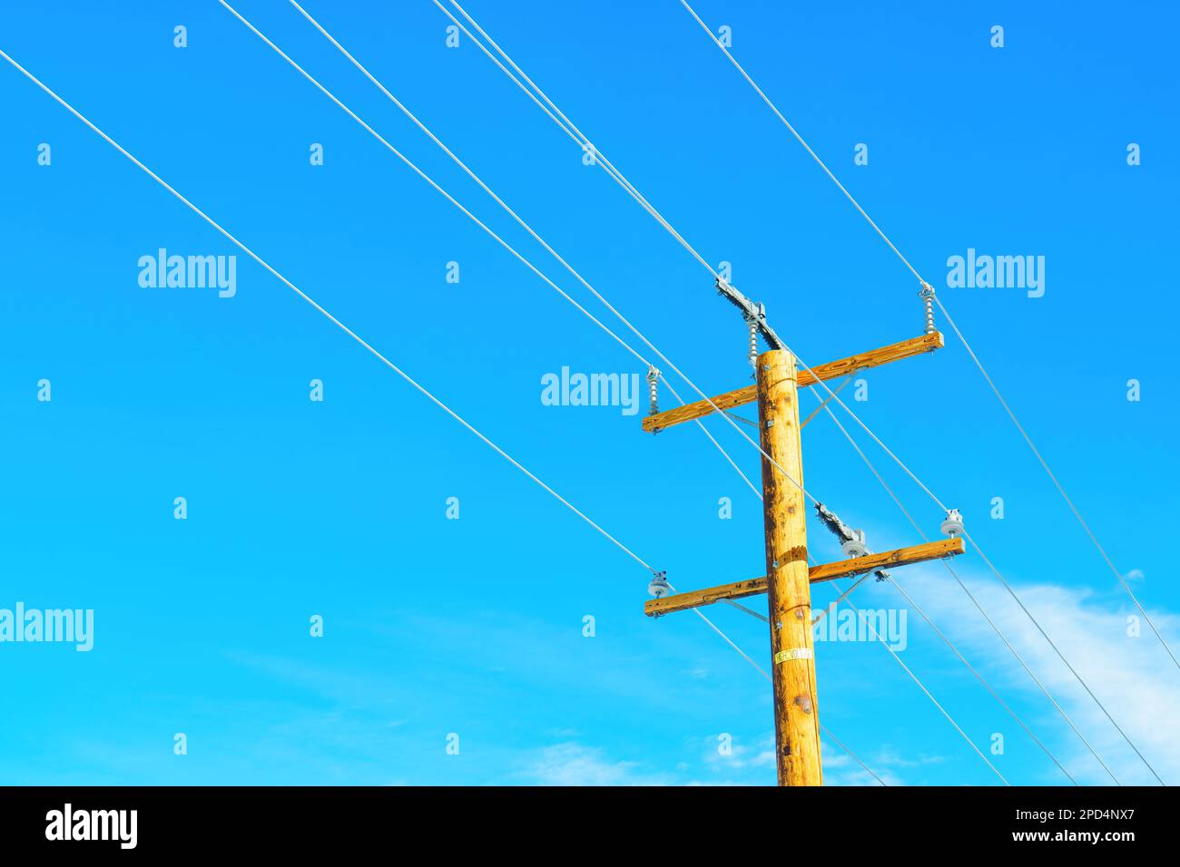 Polo di potenza in legno con fili contro un cielo blu chiaro. Energia, alimentazione, tecnologia e ingegneria di base. Foto Stock