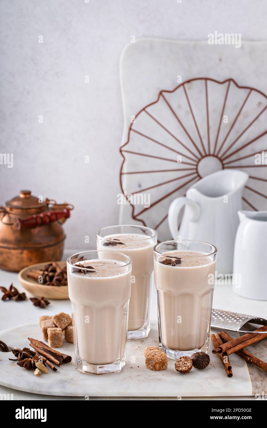 Chai fatto in casa con latte in bicchieri alti con spezie su una tavola Foto Stock