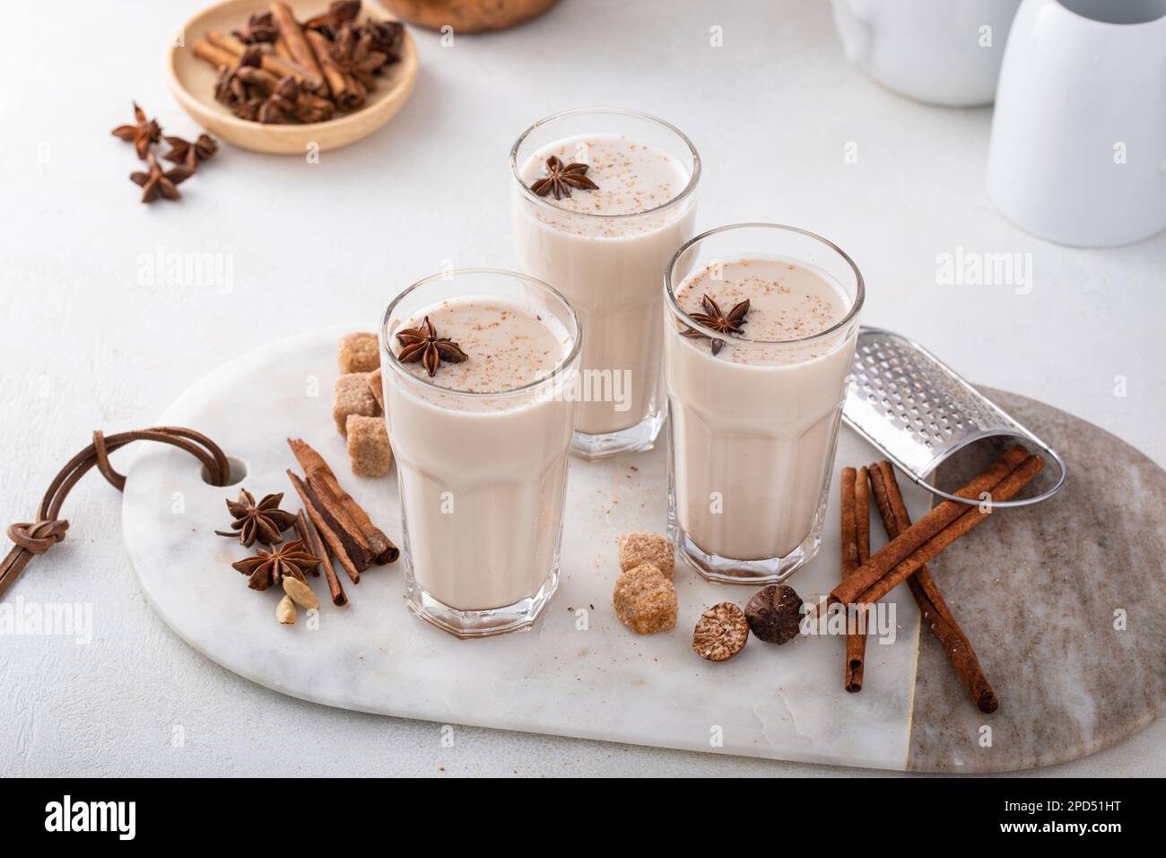 Chai fatto in casa con latte in bicchieri alti con spezie su una tavola Foto Stock