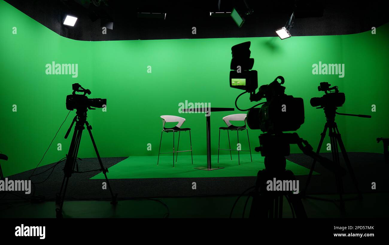 TV moderna interni Chroma Key Studio con schermo verde, luce, macchina fotografica e mobili. Studio di tiro con host e attrezzature professionali. Foto Stock