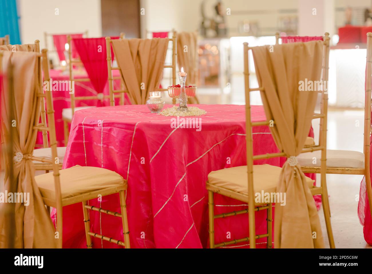 Una sala banchetti che presenta piu' tavoli rosa coperti di stoffa e adornati con candele accese Foto Stock