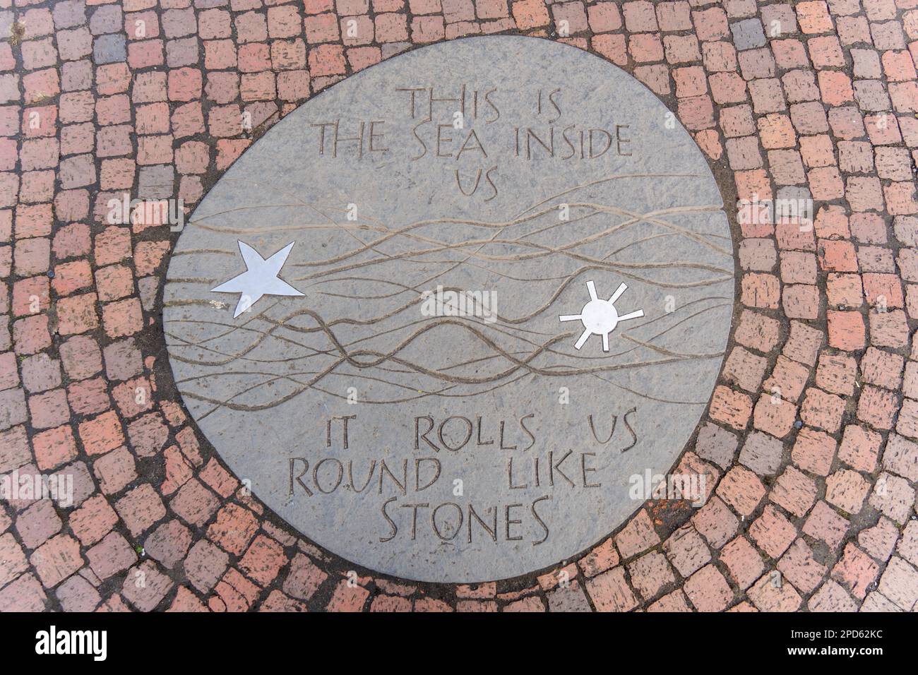 Una targa nella piazza della città di amble, Northumberland, Regno Unito, recita: "Questo è il mare dentro di noi. Ci rotola come pietre". Foto Stock