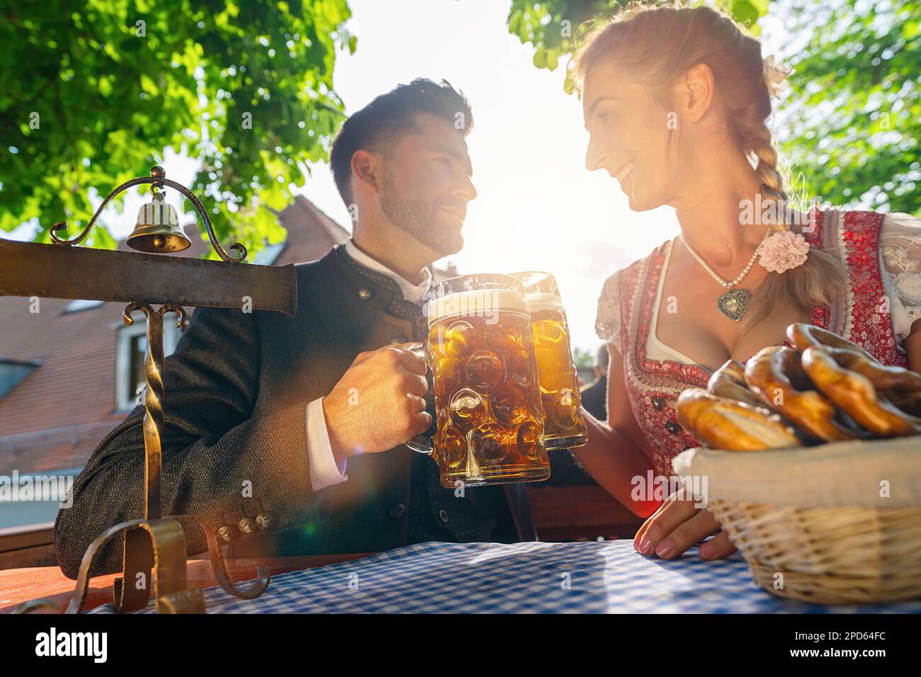 I migliori amici del Tracht bavarese seduti nella birreria all'aperto o nell'oktoberfest e sorseggiando un bicchiere di birra e il sole Foto Stock