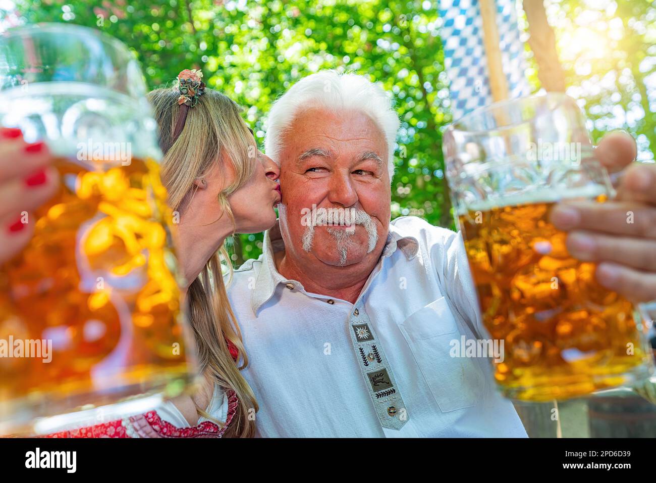La figlia dà al padre un bacio sulla guancia e dice le grazie o i bicchieri da clinking con la tazza di birra nella birreria all'aperto bavarese o nell'oktoberfest Foto Stock