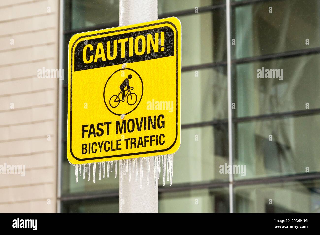 Segnale di avvertimento per i pedoni sulle biciclette veloci con i ghiaccioli sul bordo inferiore dopo il tempo estremo con la pioggia gelida Foto Stock