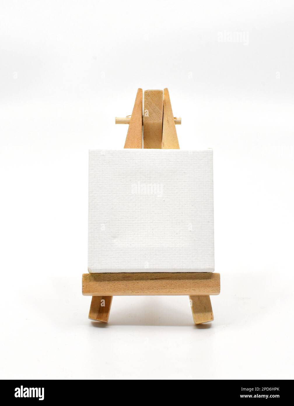 Piccolo cavalletto in legno con una tela d'arte vuota appoggiata su di esso isolata su un fondo bianco. Spazio di copia. Nessuna gente. Foto Stock