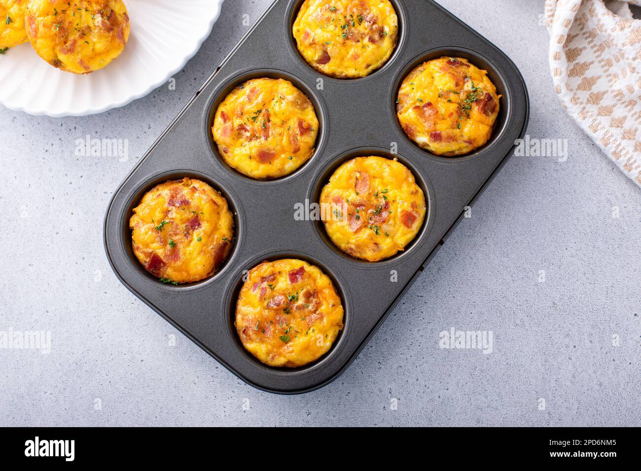 Colazione muffin o morsi di uova con patate, pancetta e cheddar in una teglia per muffin Foto Stock