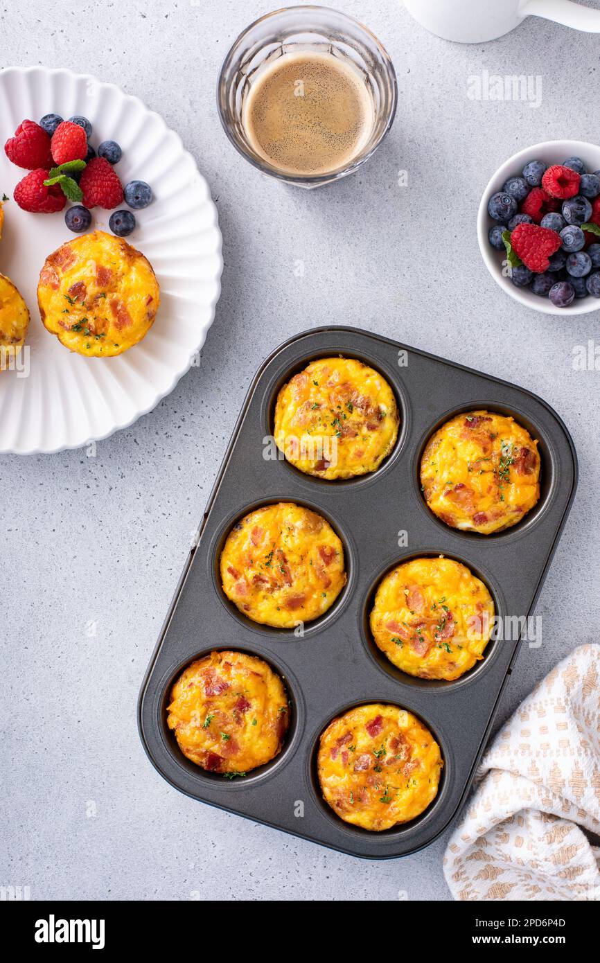 Colazione muffin o morsi di uova con patate, pancetta e cheddar in una teglia per muffin Foto Stock
