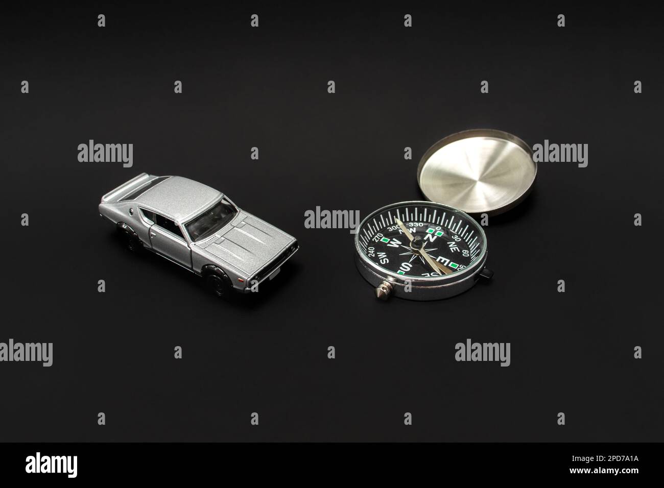 Concetto per viaggiare. Per i viaggi è necessaria una guida come una bussola o un'altra navigazione. Una foto di un'auto giocattolo e di una bussola, dopo alcune modifiche. Foto Stock