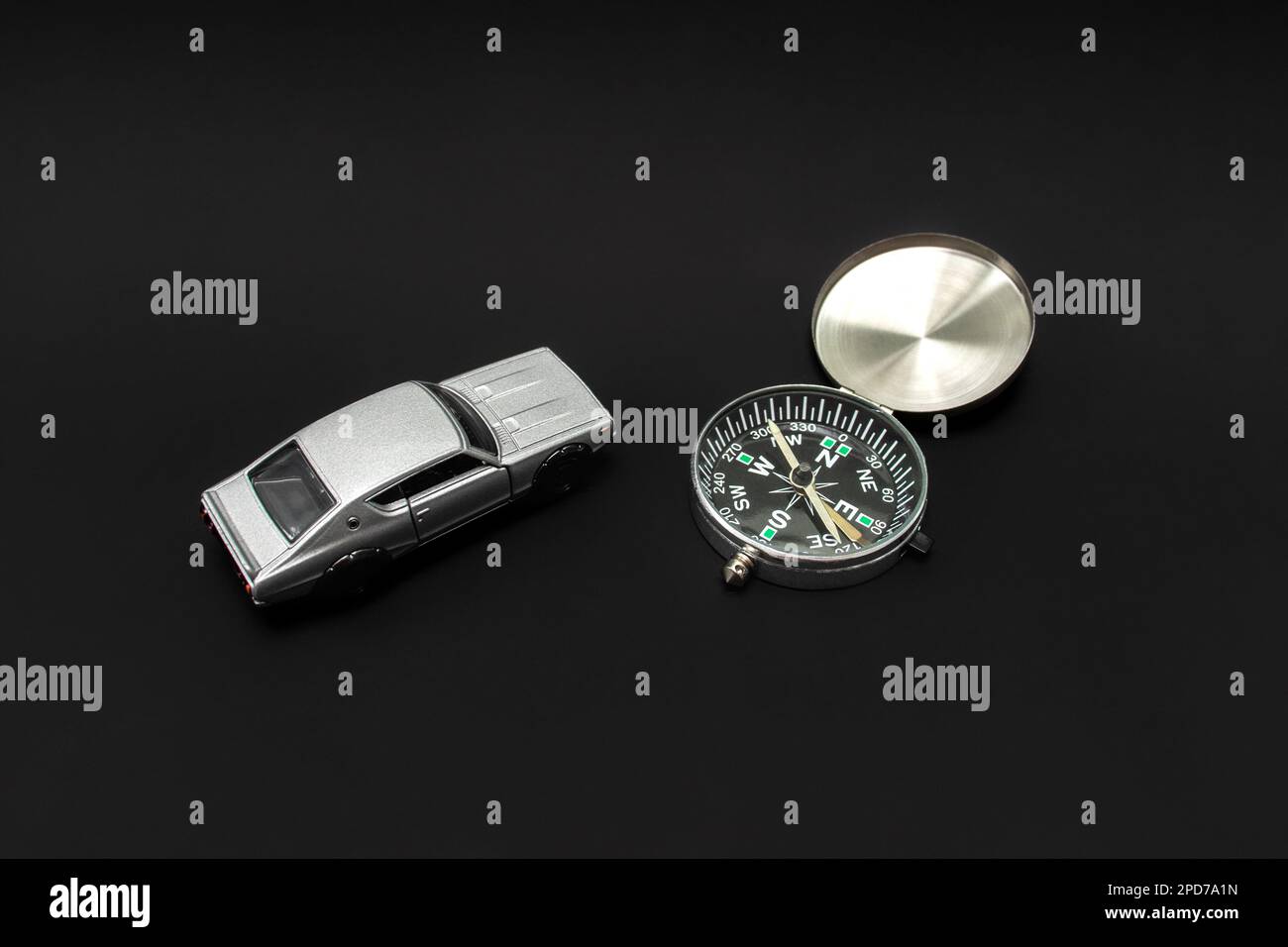 Concetto per viaggiare. Per i viaggi è necessaria una guida come una bussola o un'altra navigazione. Una foto di un'auto giocattolo e di una bussola, dopo alcune modifiche. Foto Stock