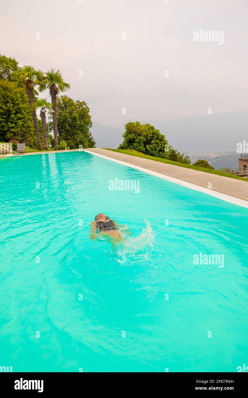 Donna nuotare in piscina con vista panoramica con montagna in Ticino, Svizzera. Foto Stock Donna nuotare in piscina con vista panoramica con montagna in Ticino, Svizzera. Foto Stock