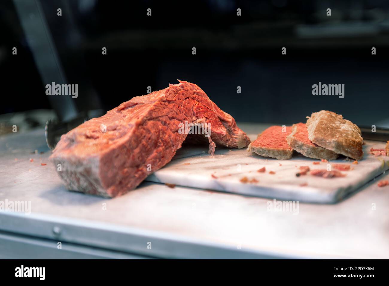 Un giunto di carne tagliata su una lastra di marmo in un negozio di gastronomia. Foto Stock