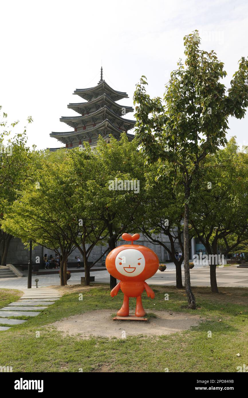 Kawaii (carino) personaggio coreano / figura nei giardini del Museo Nazionale Folcloristico della Corea a Seoul; torre del museo sullo sfondo Foto Stock