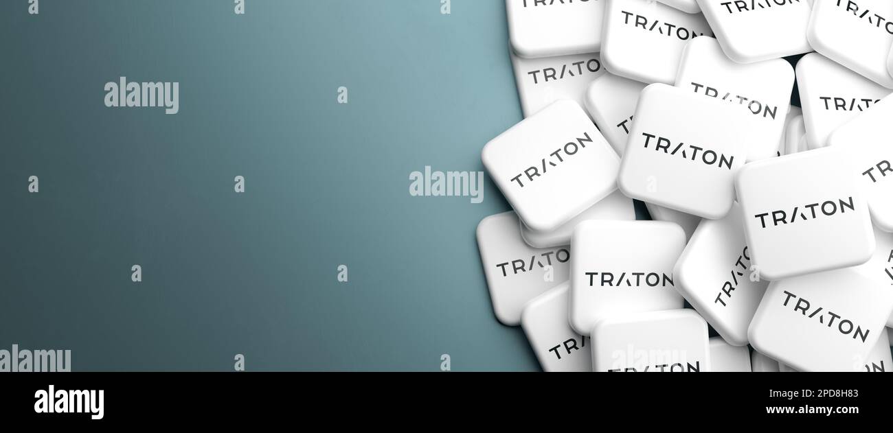 Loghi di Traton il costruttore di camion e autobus su un mucchio su un tavolo. Spazio di copia. Formato banner Web. Foto Stock