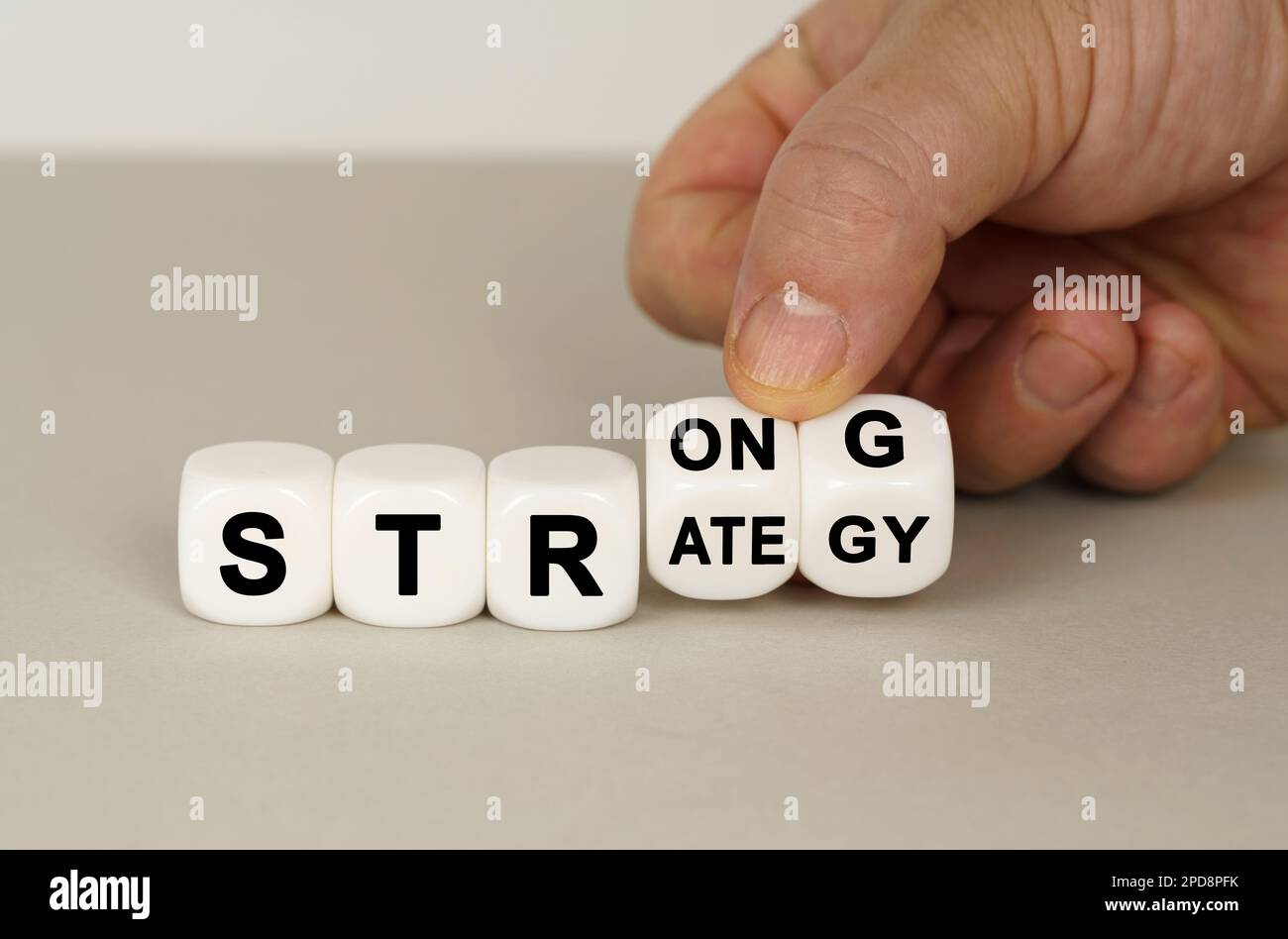 Su una superficie grigia sono i cubi bianchi con l'iscrizione - FORTE o STRATEGIA. Due dadi in mano. Concetto aziendale. Foto Stock
