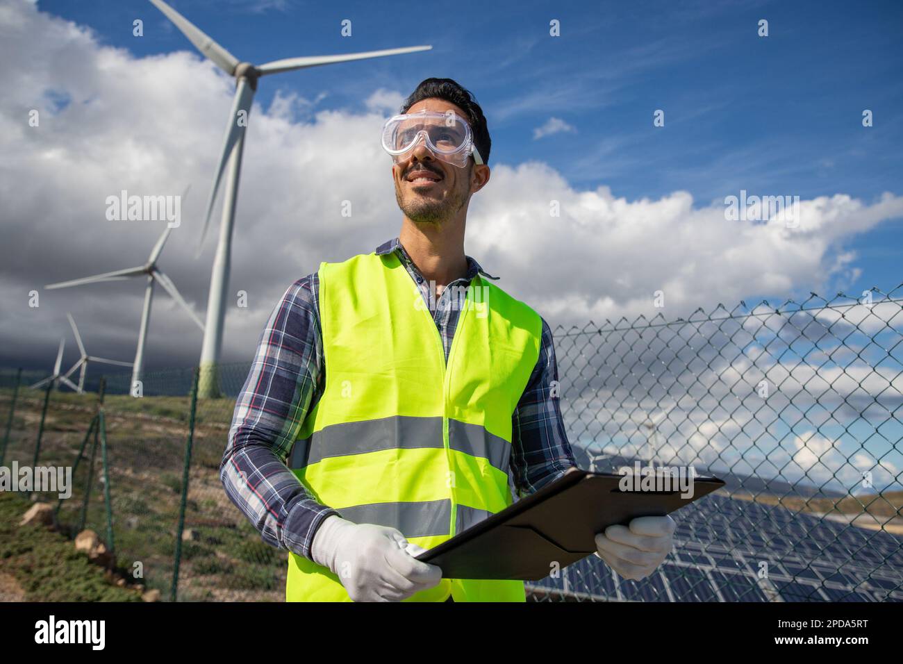 Un ingegnere in una centrale solare al lavoro, persona sicura e sorridente di successo. Foto Stock Un ingegnere in una centrale solare al lavoro, persona sicura e sorridente di successo. Foto Stock