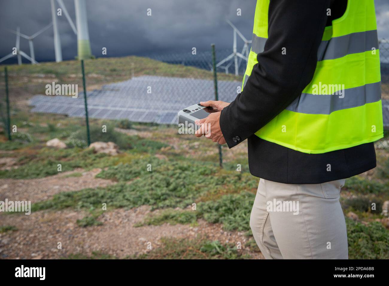 Un ingegnere è in possesso di un telecomando per far volare un drone in una centrale solare. Foto Stock Un ingegnere è in possesso di un telecomando per far volare un drone in una centrale solare. Foto Stock
