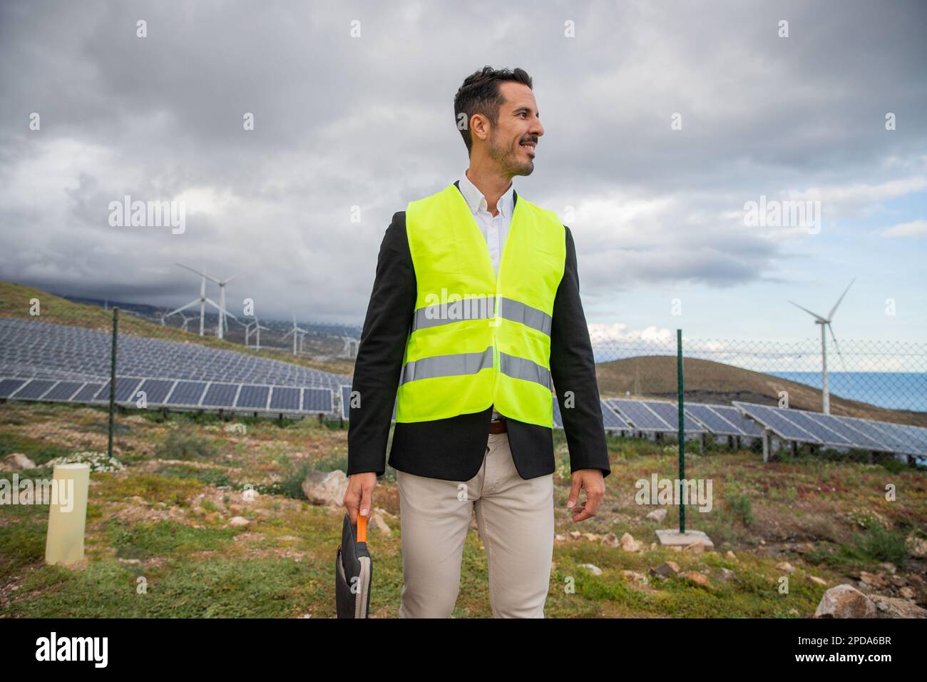 Un ingegnere tiene in mano una custodia per laptop durante un'ispezione presso la centrale solare. Foto Stock Un ingegnere tiene in mano una custodia per laptop durante un'ispezione presso la centrale solare. Foto Stock
