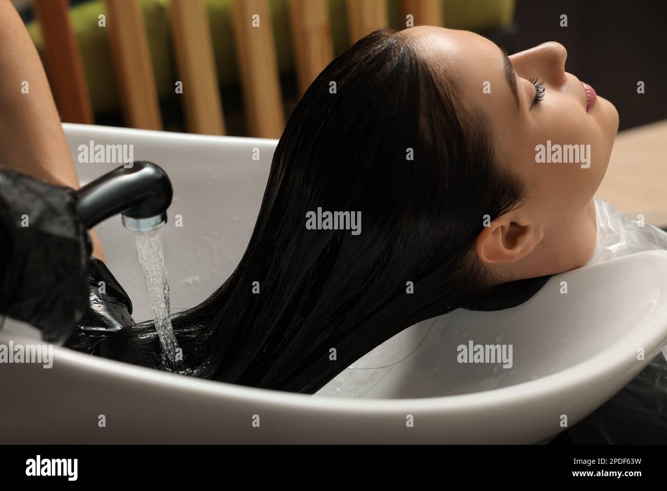 Parrucchiere che sciacqua il colorante dai capelli della donna nel salone di bellezza Foto Stock