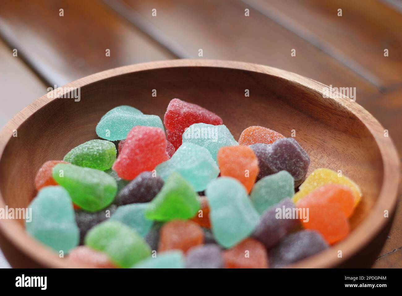 un primo piano di caramelle gommose di vari colori e sapori di frutta servite in una ciotola di legno. Foto Stock