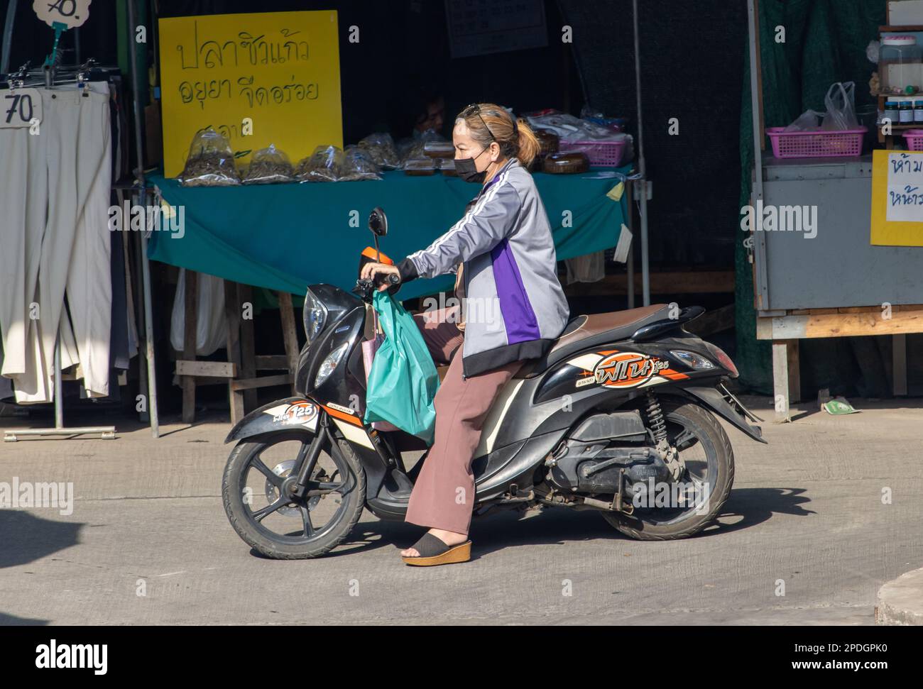 SAMUT PRAKAN, THAILANDIA, 13 2023 FEBBRAIO, Una donna cavalca una moto al mercato Foto Stock