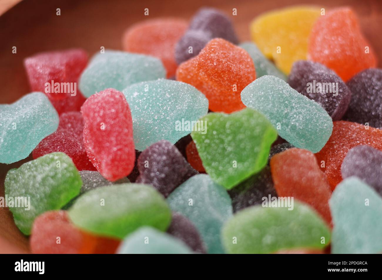 un primo piano di caramelle gommose di vari colori e sapori di frutta servite in una ciotola di legno. Foto Stock