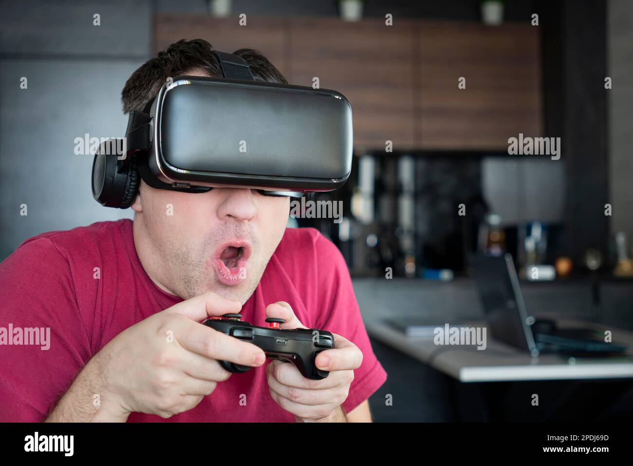 Sentirsi eccitato e stupito. Giovane uomo che indossa occhiali VR mentre gioca ai videogiochi in un mondo virtuale. Foto Stock