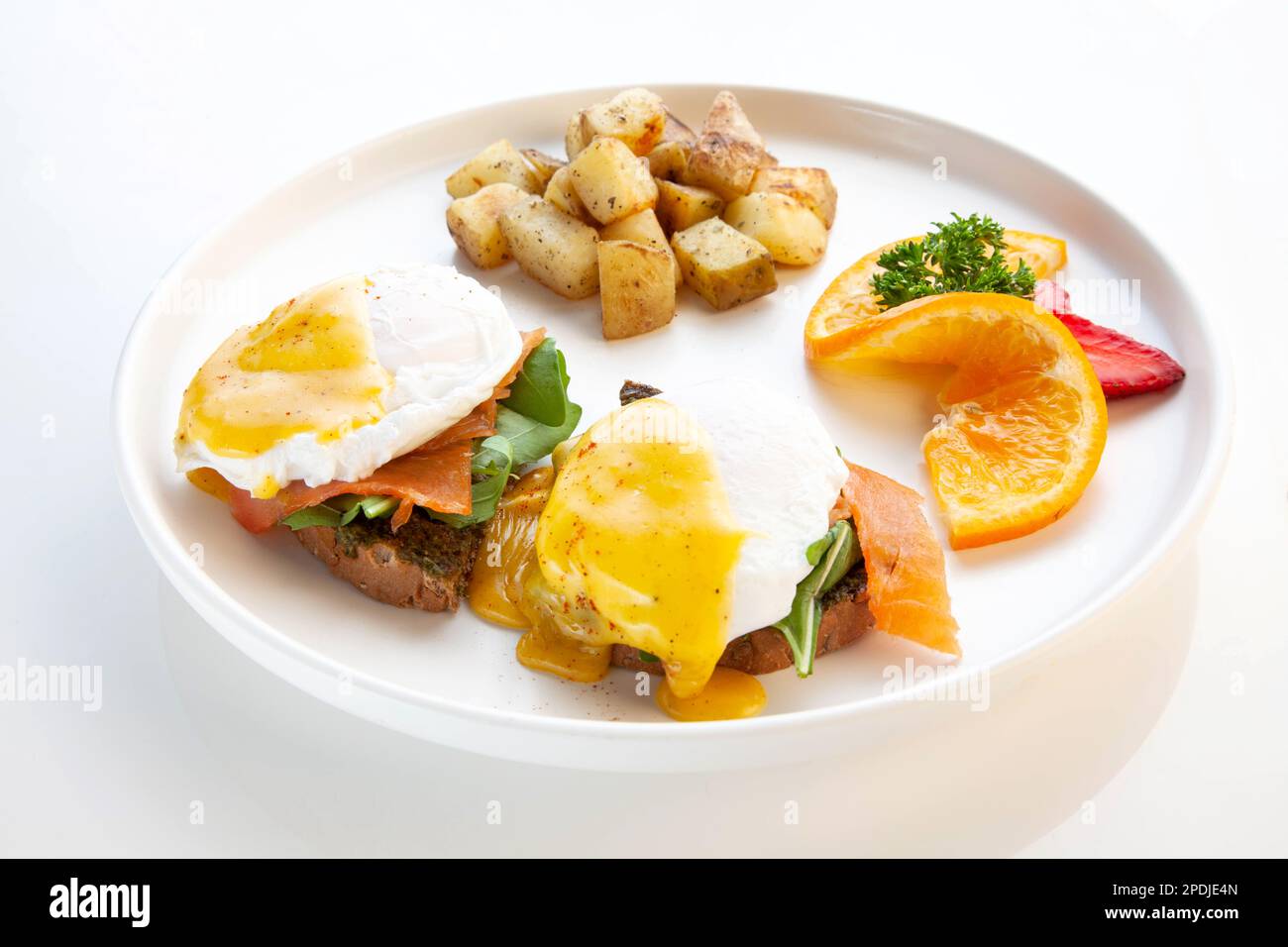 Salmone Benedict - uova in camicia, salsa di hollandaise, salmone affumicato, pesto e foglie di rucola serviti su ciabatta. Foto Stock