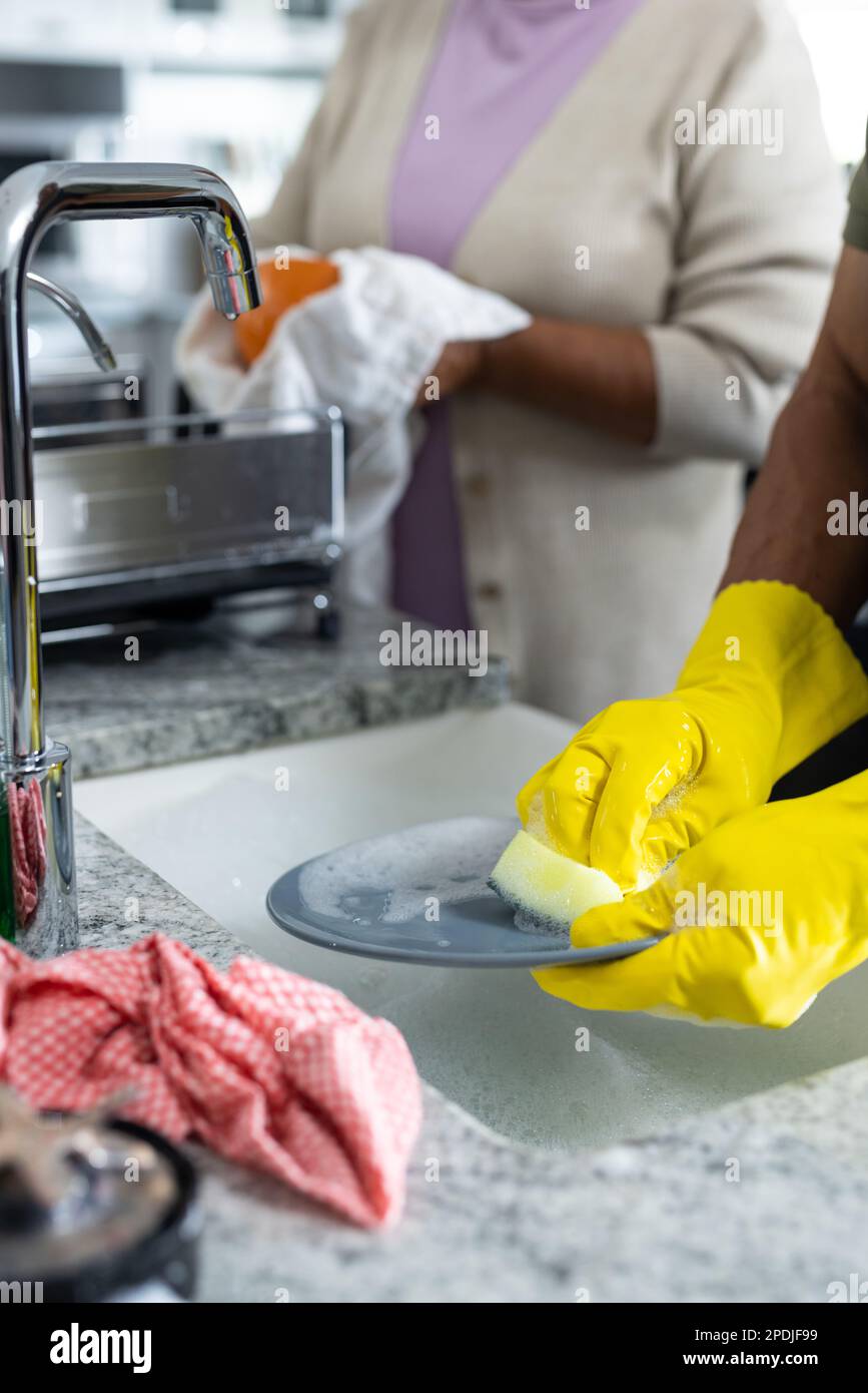Sezione centrale della coppia biraciale senior piatti di pulizia insieme in lavello cucina Foto Stock