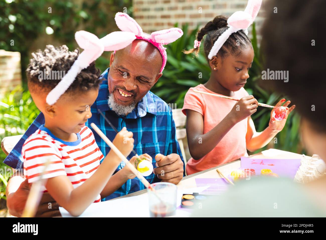 Famiglia afro-americana felice colorazione uova di pasqua in giardino Foto Stock