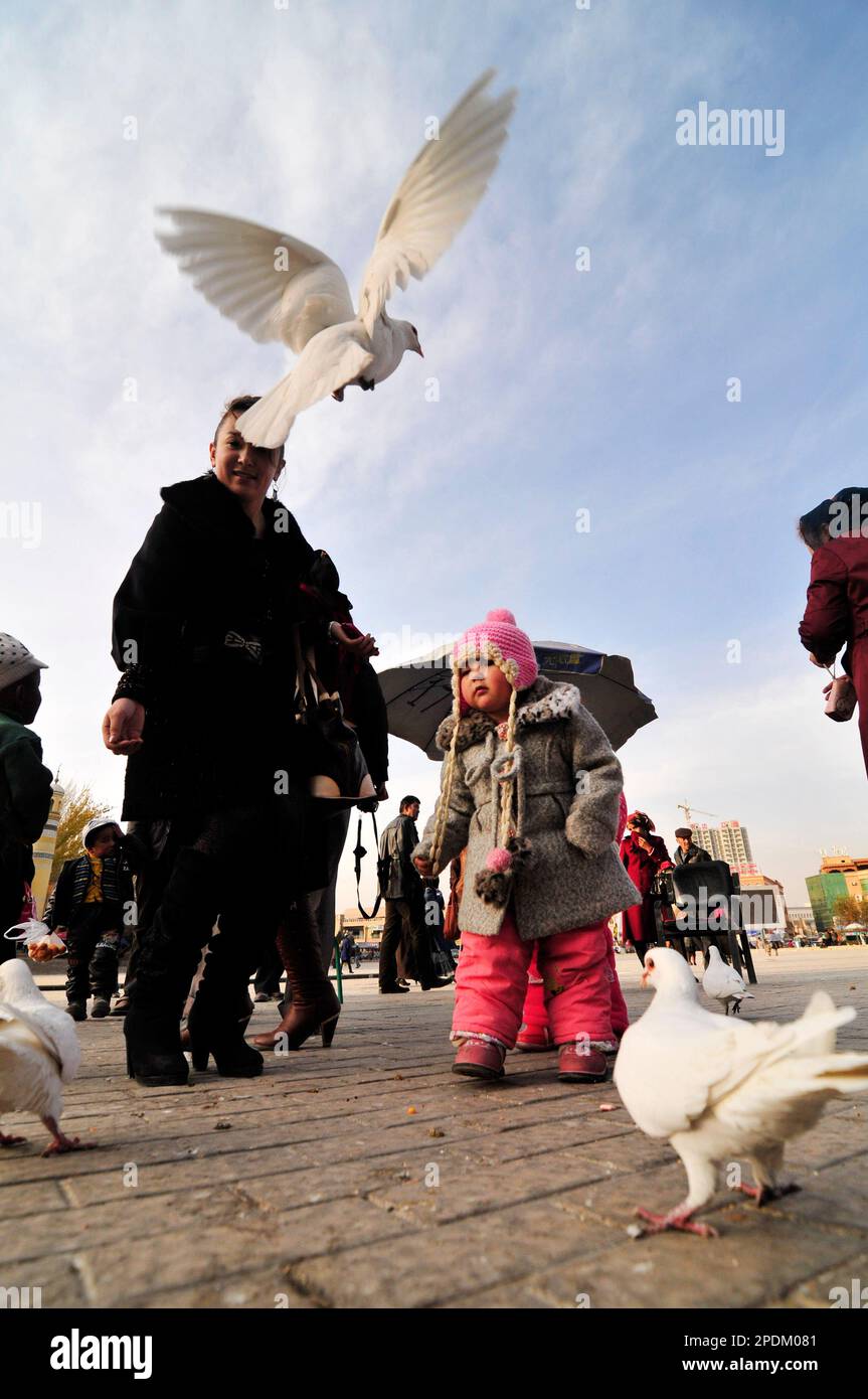 Madre e bambino di Uighur che nutrono i piccioni a Kashgar, Cina. Foto Stock