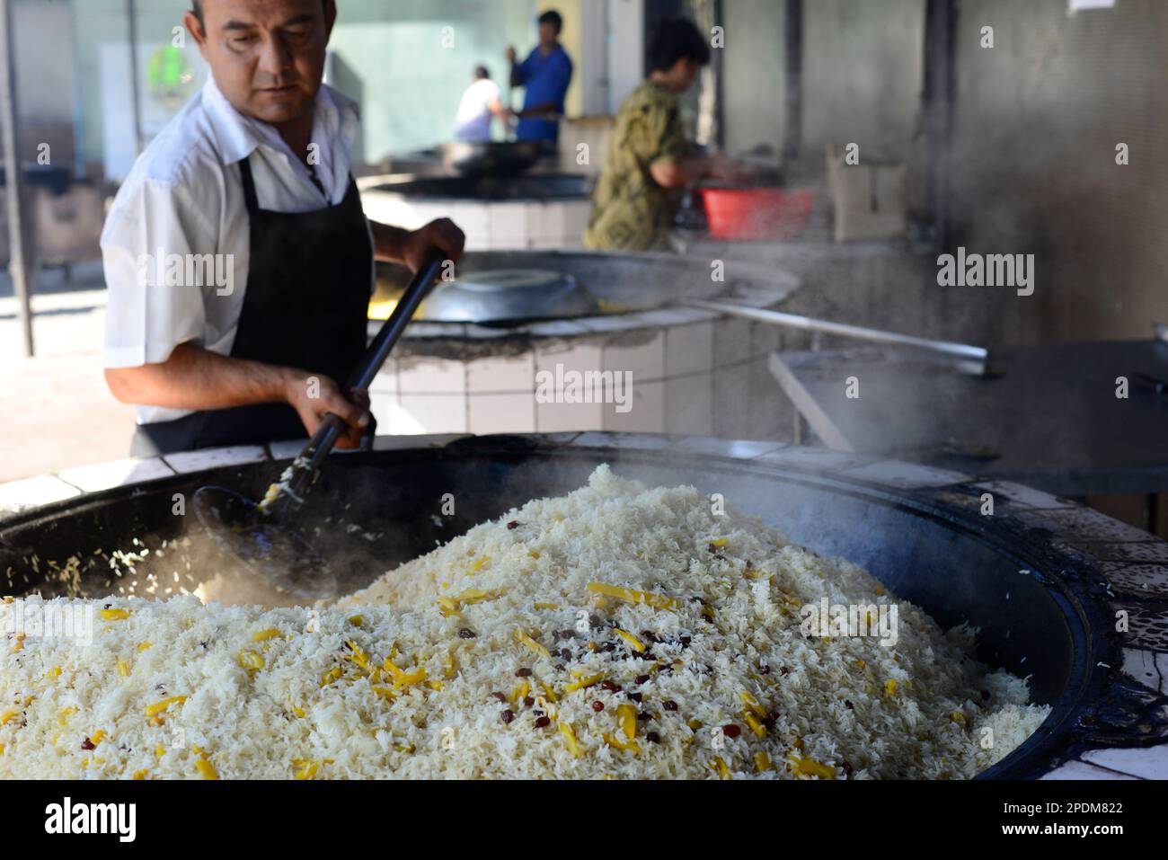 I coloni giganti traboccano con il piatto di riso preferito dell'Uzbekistan presso il centro plov dell'Asia centrale a Tashkent, Uzbekistan. Foto Stock