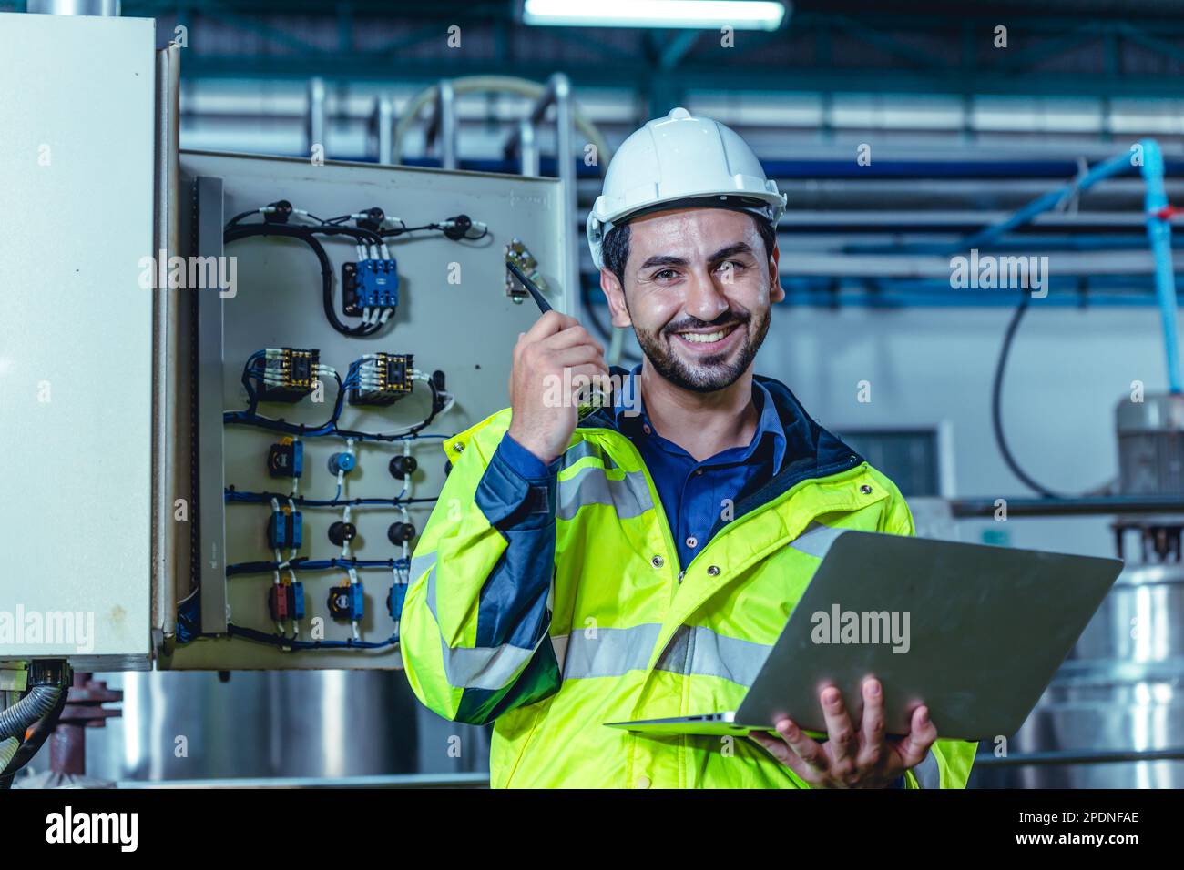 Ritratto elettricista tecnico ispanico che lavora in fabbrica per il controllo dell'armadio elettrico ad alta tensione in fabbrica. Foto Stock