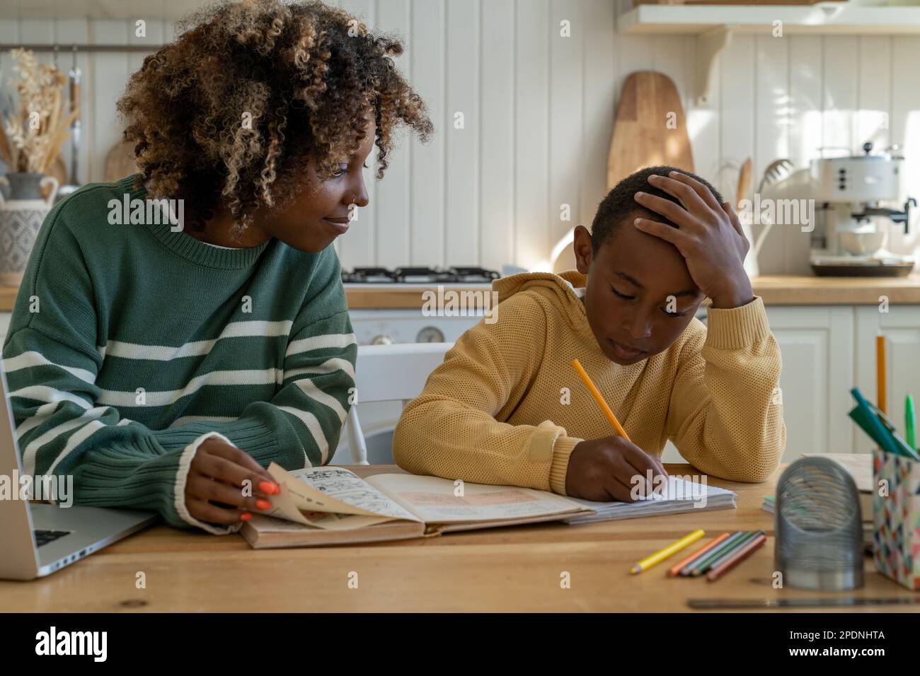 Giovane madre homeschool della donna afro-americana che aiuta il figlio con i compiti a casa Foto Stock